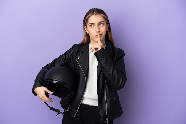 Jonge kaukasische vrouw die een geïsoleerde motorhelm houdt