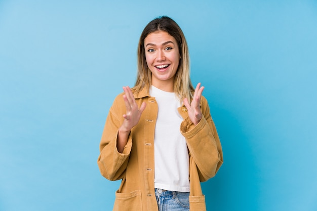 Jonge Kaukasische vrouw die een overwinning of een succes viert, is hij verrast en geschokt.