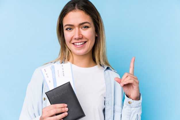 Jonge Kaukasische vrouw die een paspoort geïsoleerd houdt tonend nummer één met vinger.