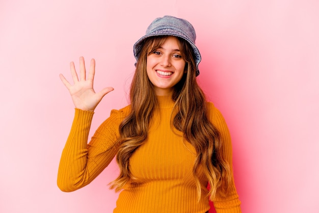 Foto jonge kaukasische vrouw die geïsoleerde vissershoed draagt ?? vrolijk glimlachend nummer vijf met vingers.