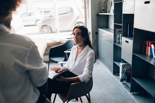 Jonge kaukasische vrouw die gesprek in moderne studio heeft