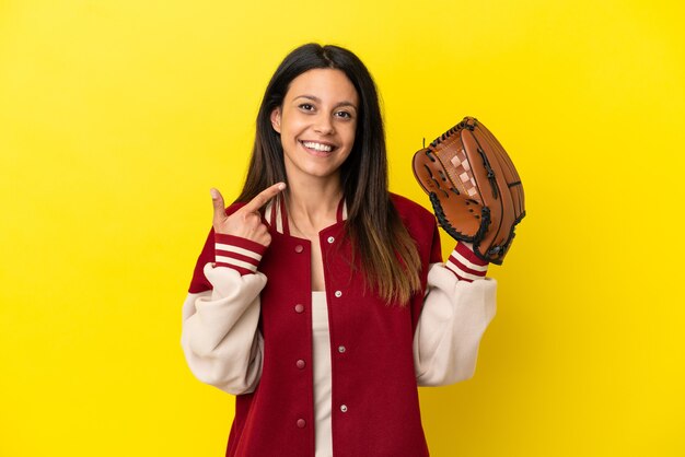 Jonge kaukasische vrouw die honkbal speelt die op gele achtergrond wordt geïsoleerd en een duim omhoog gebaar geeft