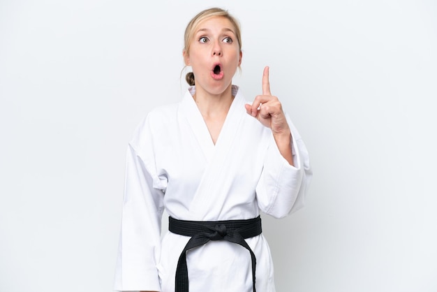 Jonge kaukasische vrouw die karate doet die op witte achtergrond wordt geïsoleerd die een idee denkt dat de vinger omhoog richt