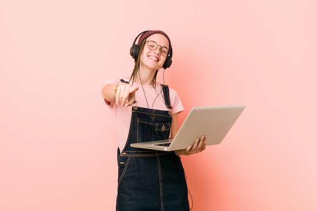 Jonge Kaukasische vrouw die laptop vrolijke glimlachen houdt richtend aan voorzijde.