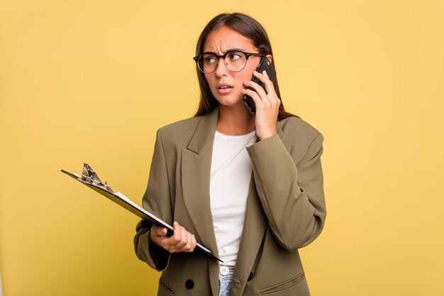 Jonge kaukasische vrouw die met geïsoleerde mobiele telefoon spreekt