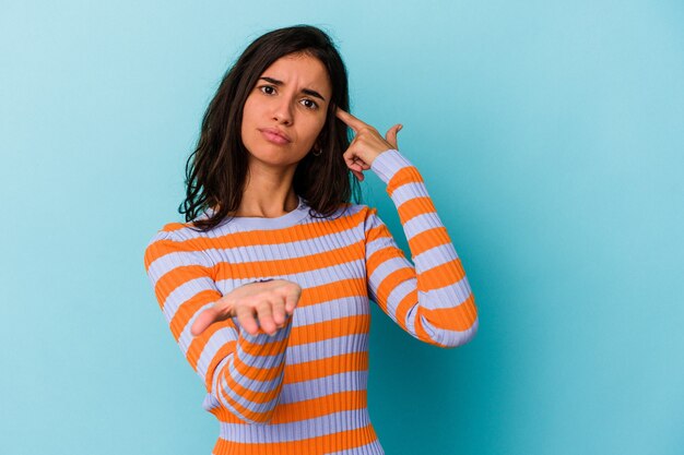 Jonge kaukasische vrouw die op blauwe achtergrond wordt geïsoleerd die een product bij de hand houdt en toont.