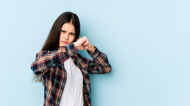 Jonge Kaukasische vrouw die op blauwe muur een stempel werpt