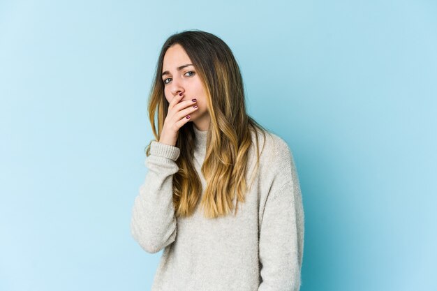 Jonge kaukasische vrouw die op blauwe muur wordt geïsoleerd die mond behandelt met handen die bezorgd kijken.