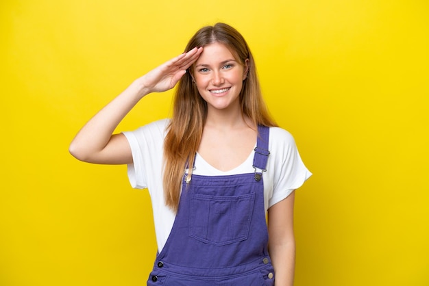 Jonge kaukasische vrouw die op gele achtergrond wordt geïsoleerd die met hand met gelukkige uitdrukking groeten