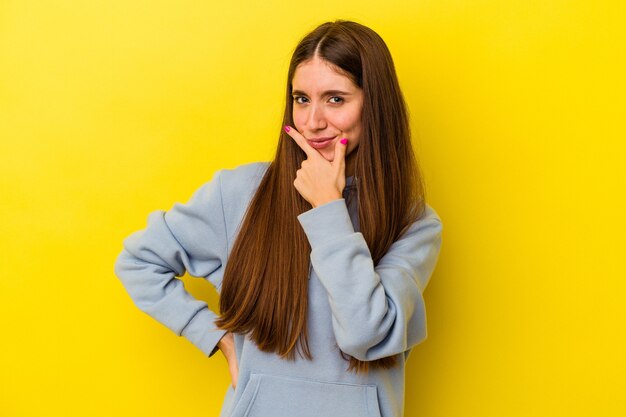 Jonge kaukasische vrouw die op gele achtergrond wordt geïsoleerd die overweegt, een strategie plant, over de manier van zaken denkt.