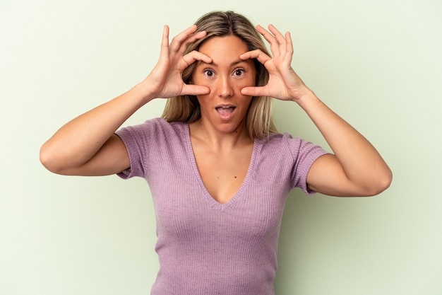 Foto jonge kaukasische vrouw die op groene achtergrond wordt geïsoleerd die ogen open houdt om een succeskans te vinden.