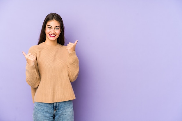 Jonge kaukasische vrouw die op purpere muur wordt geïsoleerd die beide duimen opheft, glimlachend en zelfverzekerd.