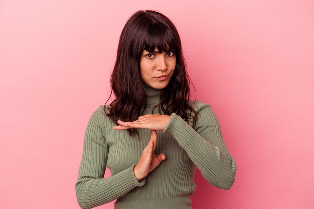 Jonge kaukasische vrouw die op roze achtergrond wordt geïsoleerd die een time-outgebaar toont.