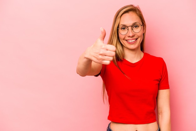 Jonge kaukasische vrouw die op roze achtergrond wordt geïsoleerd die en duim glimlacht opheft