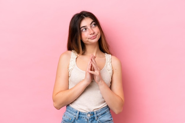 Jonge kaukasische vrouw die op roze achtergrond wordt geïsoleerd die iets plant