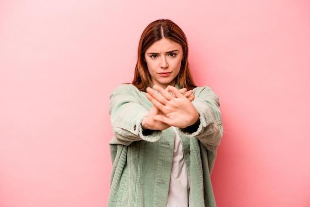 Jonge kaukasische vrouw die op roze achtergrond wordt geïsoleerd die zich met uitgestrekte hand bevindt die stopteken toont dat u verhindert