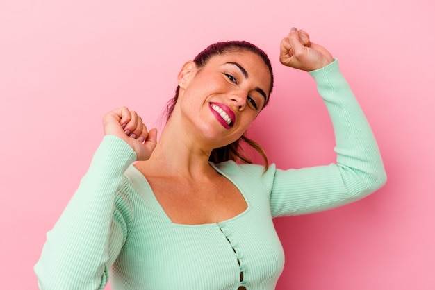 Jonge kaukasische vrouw die op roze met vingers op lippen wordt geïsoleerd die een geheim houden.