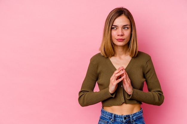 Jonge kaukasische vrouw die op roze muur wordt geïsoleerd die plan in mening, het opzetten van een idee bedenkt.