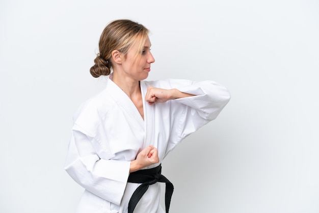 Jonge kaukasische vrouw die op witte achtergrond wordt geïsoleerd die karate doet