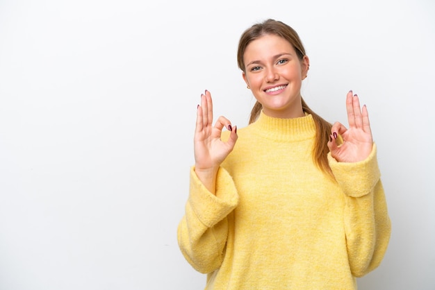 Jonge kaukasische vrouw die op witte achtergrond wordt geïsoleerd die ok teken met twee handen toont