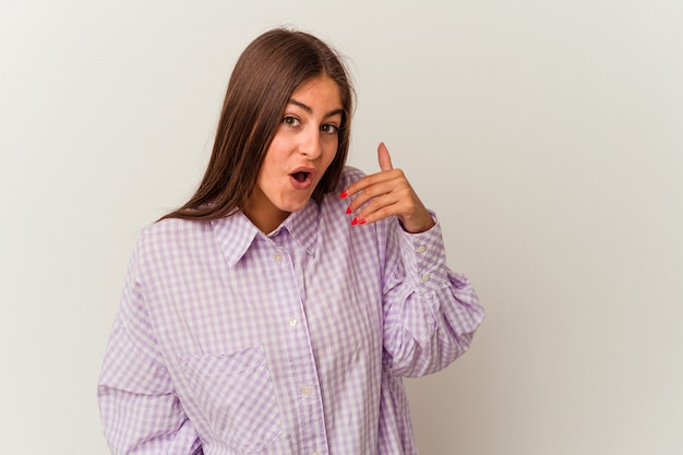 Jonge kaukasische vrouw die op witte muur wordt geïsoleerd die iemand verwerpt die een gebaar van walging toont.