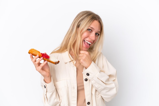 Jonge kaukasische vrouw die sashimi houdt die op witte achtergrond wordt geïsoleerd en een overwinning viert