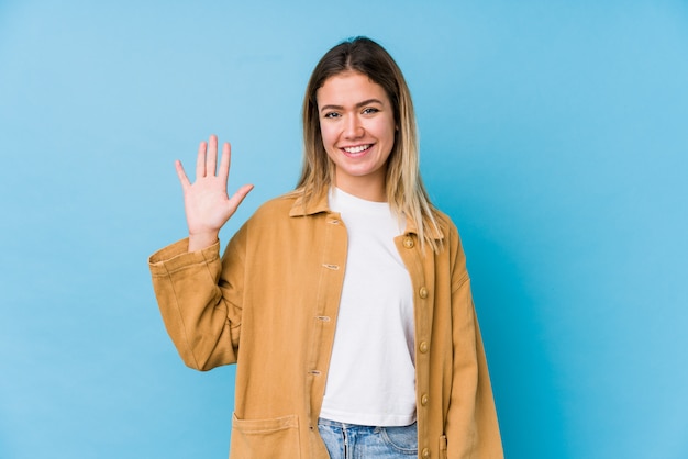 Jonge Kaukasische vrouw die vrolijk tonend nummer vijf met vingers glimlachen.