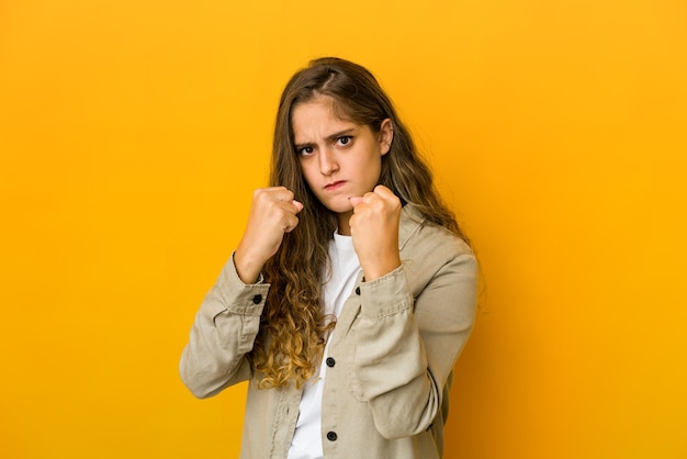 Jonge kaukasische vrouw die vuist toont aan camera, agressieve gezichtsuitdrukking.