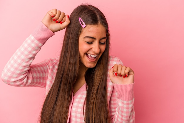 Jonge kaukasische vrouw geïsoleerd op roze muur die een speciale dag viert, springt en hef armen op met energie.