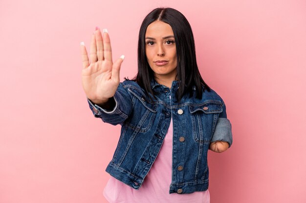 Jonge kaukasische vrouw met één arm geïsoleerd op een roze achtergrond, staande met uitgestrekte hand die een stopbord toont, waardoor je wordt verhinderd.