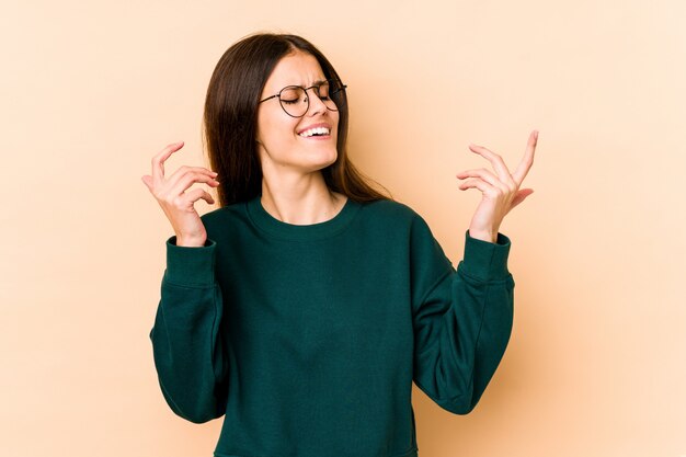 Jonge Kaukasische vrouw op beige muur blij lachen veel.