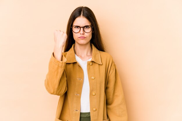 Jonge Kaukasische vrouw op beige muur die vuist toont