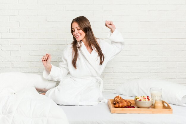 Jonge kaukasische vrouw op het bed dat en pret danst heeft.