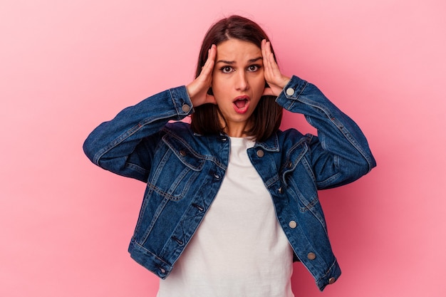 Jonge kaukasische vrouw op roze achtergrond die pret heeft die de helft van gezicht met palm behandelt.