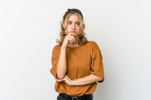 Jonge Kaukasische vrouw op witte en muur die omhoog denken kijken