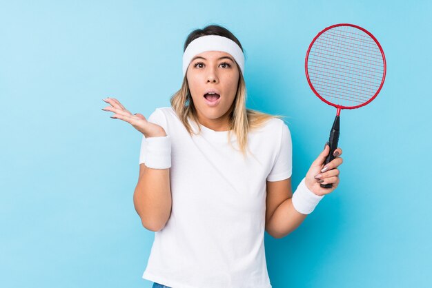 Jonge Kaukasische vrouw verrast en geschokt badminton spelen.