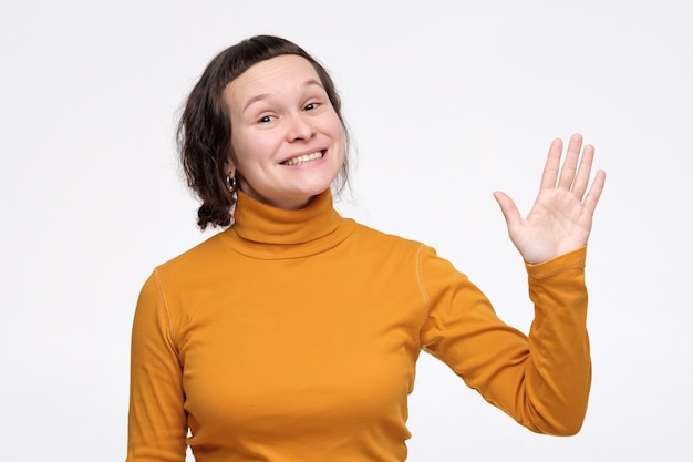 Jonge Kaukasische vrouwen golvende hand die hallo of vaarwel zegt