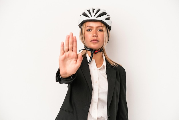 Jonge kaukasische zakenvrouw die een fietshelm draagt die op witte achtergrond wordt geïsoleerdd die zich met uitgestrekte hand bevindt die stopteken toont, die u verhinderen.