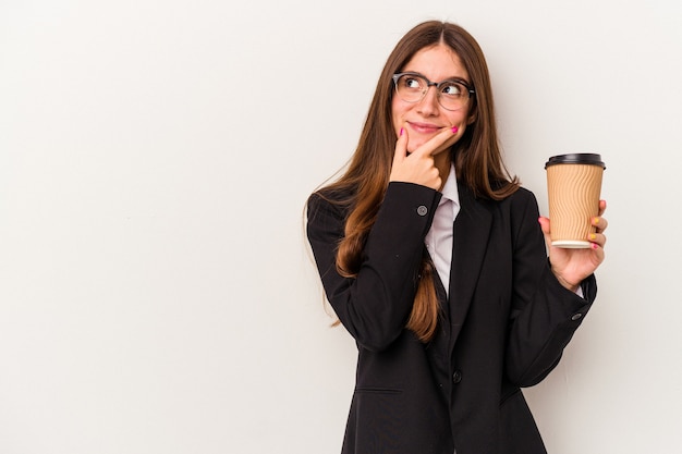 Jonge Kaukasische zakenvrouw met een afhaalmaaltijden koffie geïsoleerd op een witte achtergrond zijwaarts kijkend met twijfelachtige en sceptische uitdrukking.