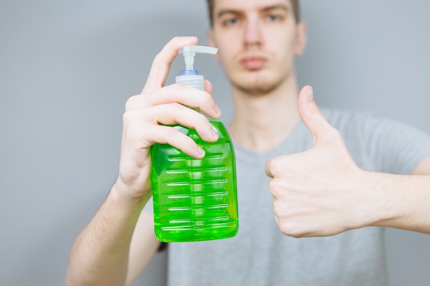 Jonge kerel behandelt zijn handen met een antisepticum