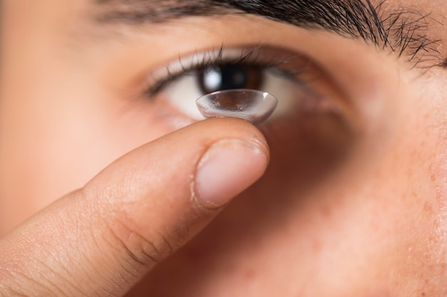 Jonge kerel die een lens op zijn vinger houdt