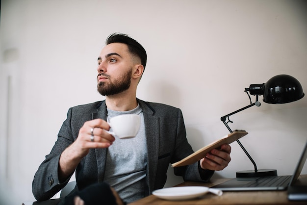 Foto jonge kerel die koffie drinkt tijdens het werk