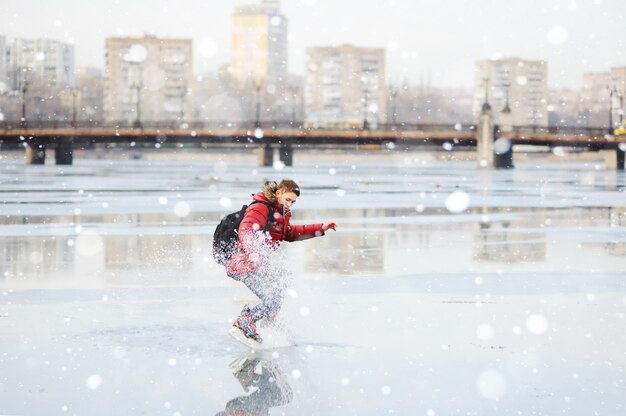 Jonge kerel die op een stadsijsbaan schaatsen op een bevroren vijver