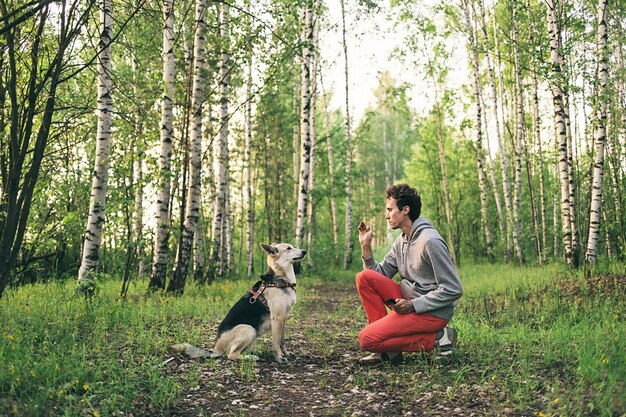 Jonge kerel leert hond poot te geven in het bos