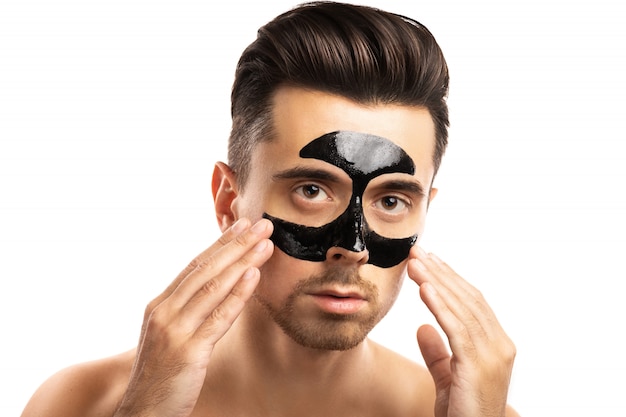 Jonge kerel met een zwart houtskoolmasker op zijn gezicht op wit.