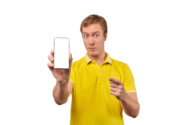 Jonge kerel met smartphone mockup in de hand witte geïsoleerde achtergrond Peinzende man in gele T-shirt met mobiele telefoon mock up met wit scherm grappige kerel met mobiele app advertentie