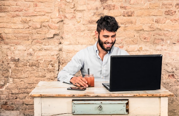 Jonge kerelzitting bij uitstekend bureau met laptop