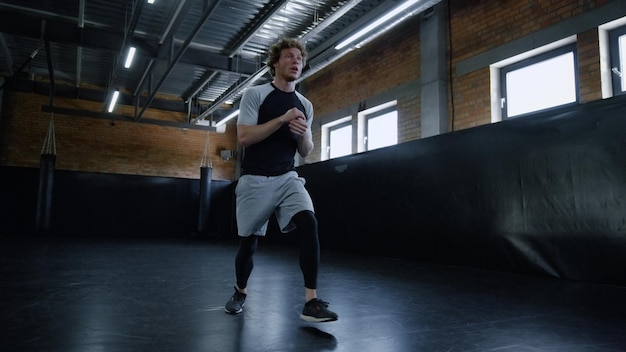Jonge kickbokser doet lunges op sportschool Sportman maakt oefeningen in sportclub