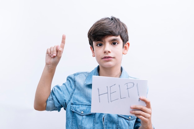 Jonge kleine jongen jongen houdt papier zingen met hulpbericht om bescherming te vragen verrast met een idee of vraag wijzende vinger met blij gezicht, nummer één