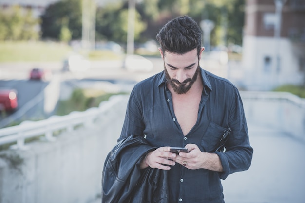 jonge knappe aantrekkelijke bebaarde model man met smartphone